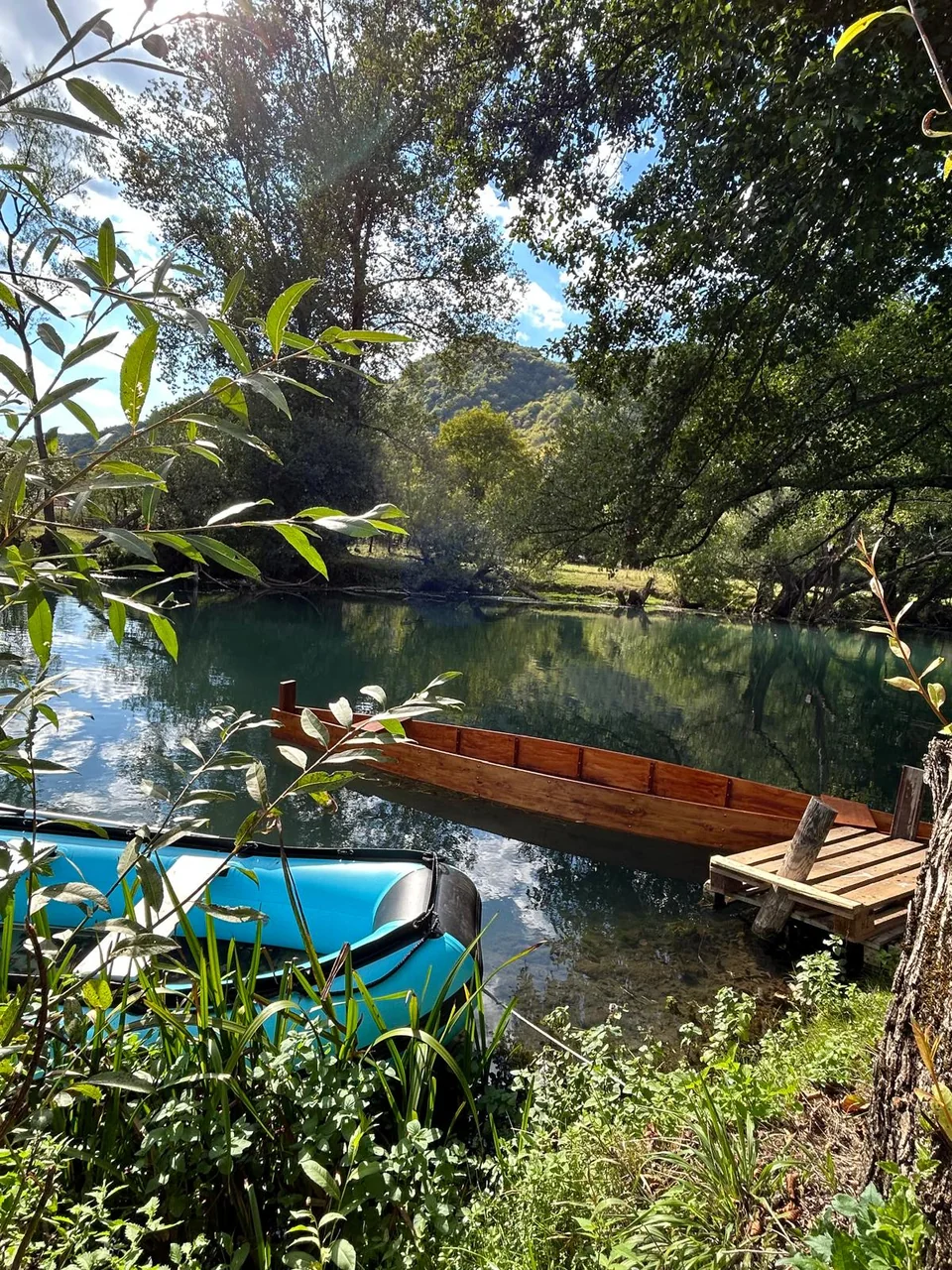 Holzboot und Schlauchboot am bewaldeten Pliva-Ufer